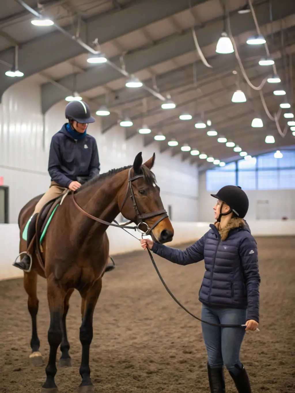 An adult rider receiving guidance from a certified instructor during a training session in a well-equipped equestrian facility.